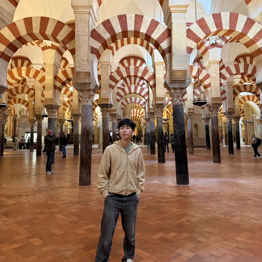 Ethan standing among the red-and-white striped arches of the Mosque-Cathedral of Córdoba