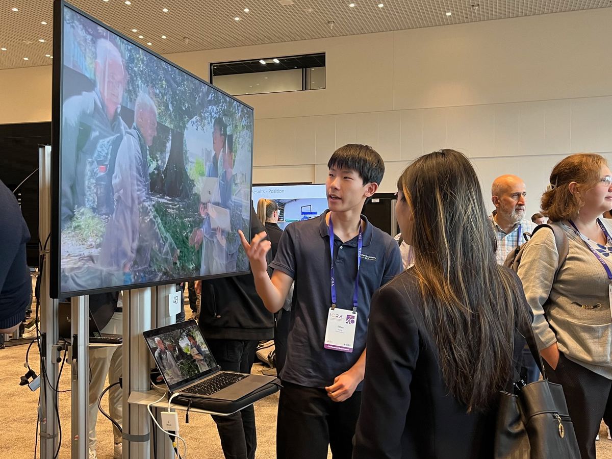 Ethan presenting his Food Angel video to visitors at ICRA@40, wearing a conference badge