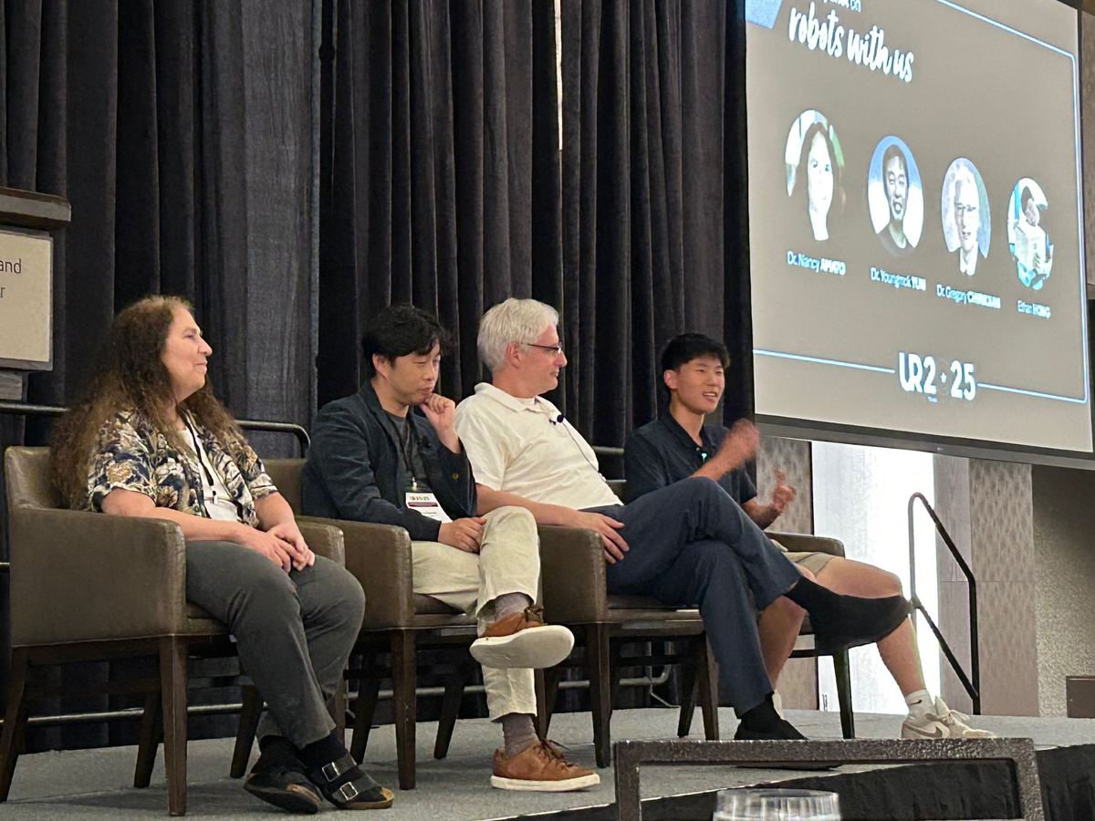 Ethan speaking on a conference panel alongside three professors, under a slide reading Special panel on robots with us