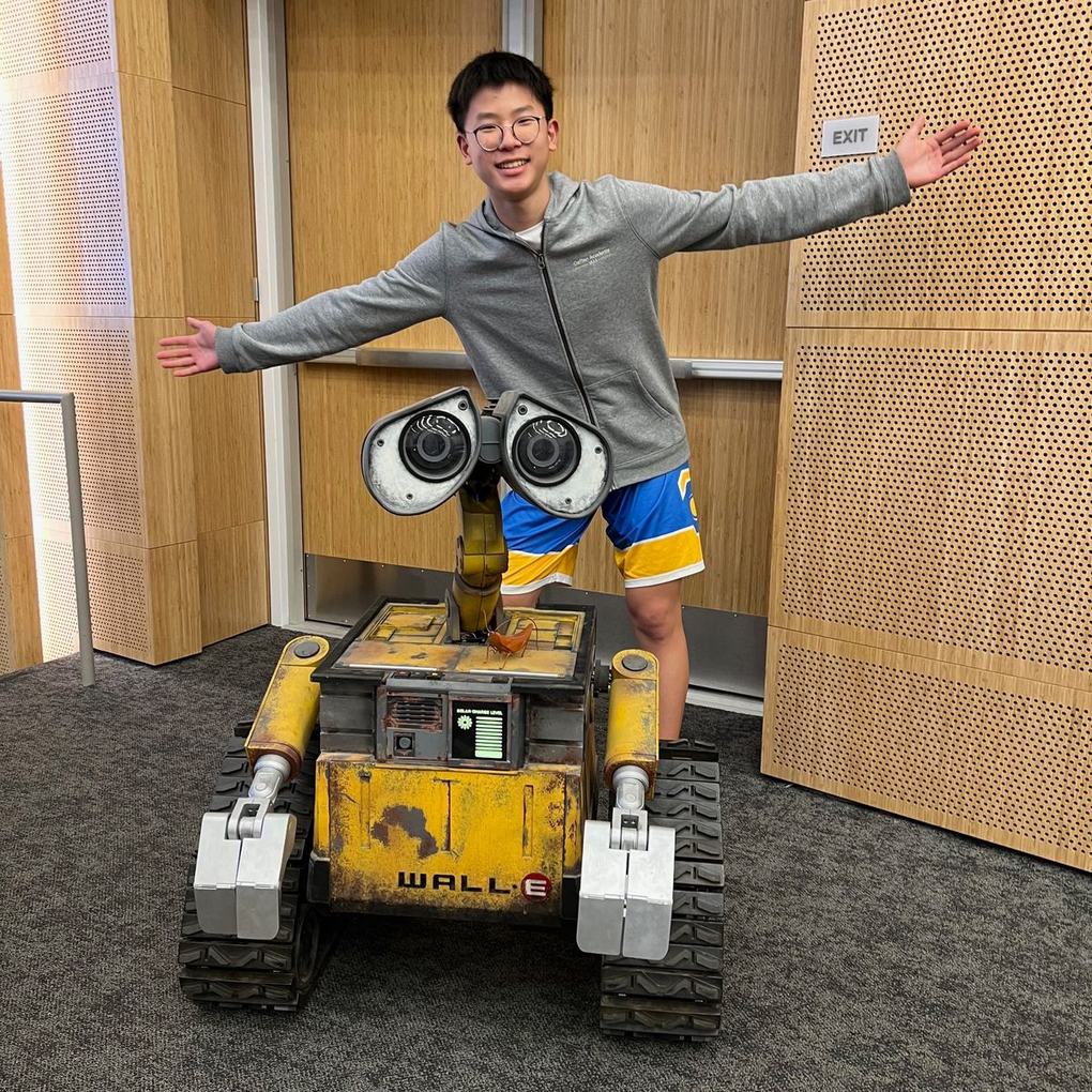 Ethan with his arms outstretched behind a life-size WALL-E replica