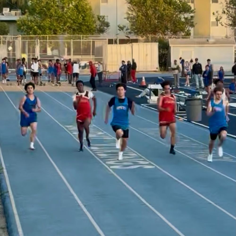 Ethan racing in the middle of a pack of sprinters on a blue track