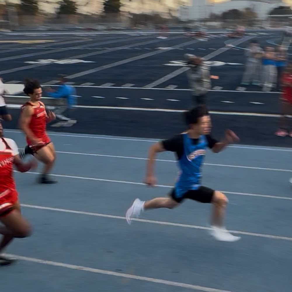Ethan sprinting down the straightaway in a blue Geffen singlet